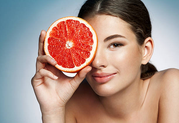 istock Glossy girl with grapefruit cut in half fruit in hand 516487379