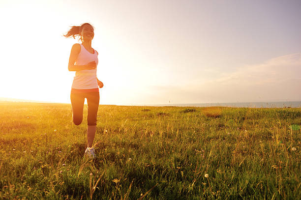 Runner athlete running on sunrise/sunset grass field
