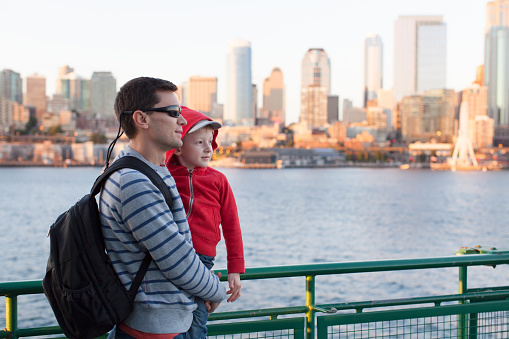 family of two enjoying ferry boat ride in seattle with great city skyline view at sunset