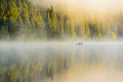 Silhoutte of two men rowing a boat and fishing in the early morning.  Trilium Lake, Oregon