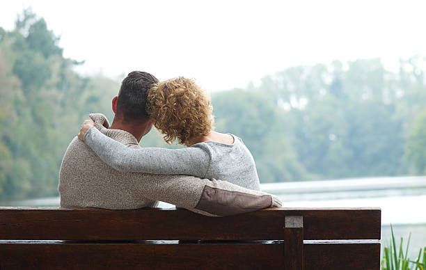 istock Couple sitting on bench by the lake 516490909