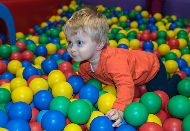 istock Baby boy with hearing aid crawls in a ball pool 516492020