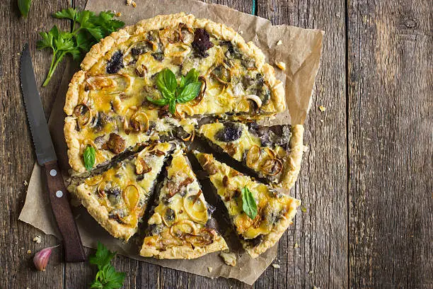 tart with mushrooms, leek and cheese on rustic background