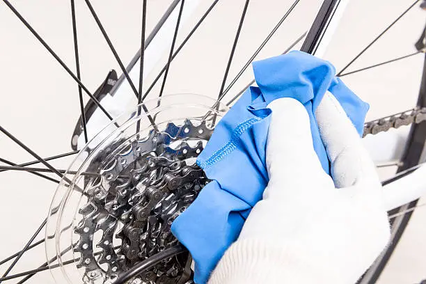 Preparing bicycle for a new season. Hand with cloth cleaning derailleur