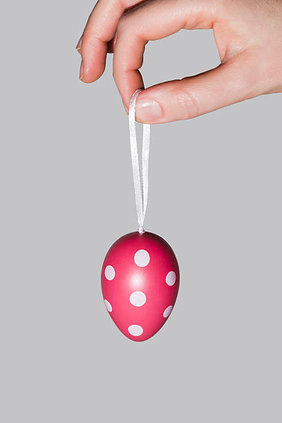 istock Female hand holding a rope with an Easter dyed egg 516494432