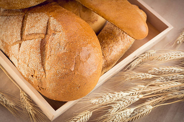 istock Wooden tray with various bread and wheat sheaf 516494466