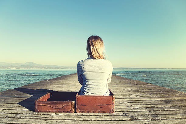 relaxed woman sitting in her big suitcase after a journey