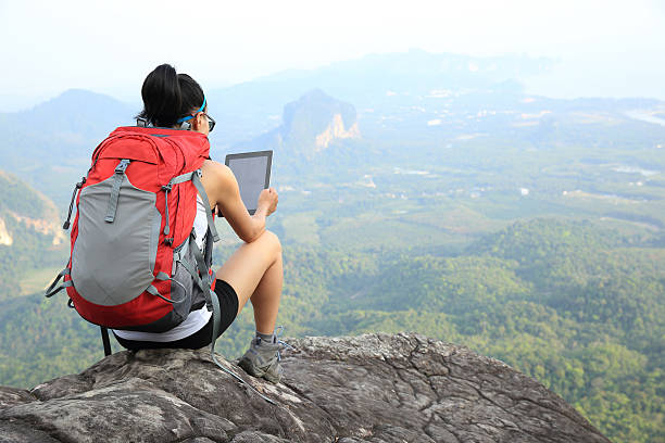 istock woman hiker use digital tablet at mountain peak cliff 516498104