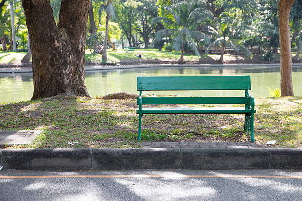 istock Green benches beside walkway in the park. 516498110