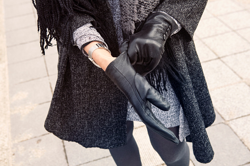 close-up of woman standing in the street putting on her black leather gloves