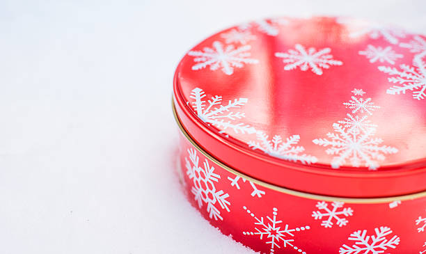 istock Round, red, Christmas snowflake cookie container tin on natural snow. 516498646