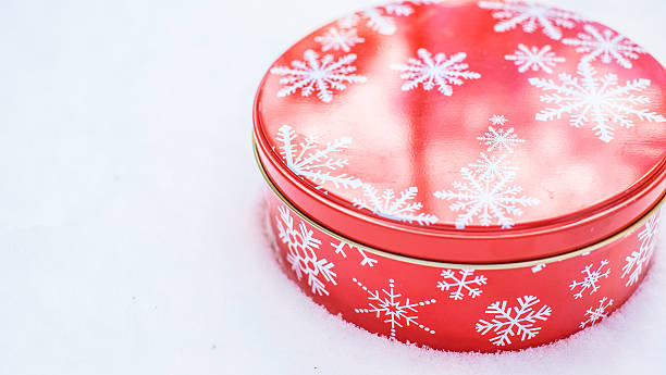 istock Round, red, Christmas snowflake cookie container tin on natural snow. 516499256