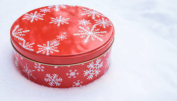 istock Round, red, Christmas snowflake cookie container tin on natural snow. 516499528
