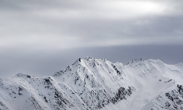 istock High snowy mountains and gray sky before blizzard 516499622