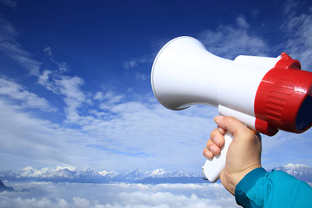 istock hand hold loudspeaker to blue sky on mountain peak 516503340
