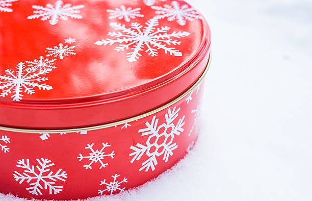 istock Round, red, Christmas snowflake cookie container tin on natural snow. 516505722