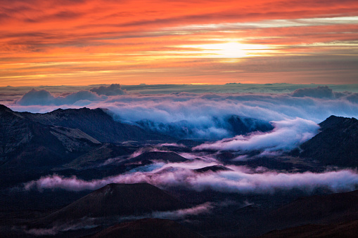 The sunrise in the Haleakala National Park Crater in Maui, Hawaii. A volcanic crater on the peak of the Haleakala Volcano on top of the island of Maui. Over 10,000 feet above sea level, an incredible view from the crater at sunrise. A popular tourist destination all day, especially at sunrise and sunset. Photographed in horizontal format.