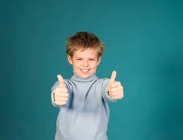 istock Happy boy showing thumbs up gesture, isolated over blue background. 516507709