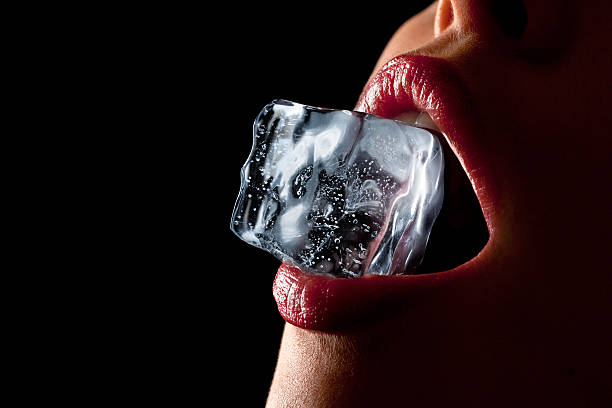 Ice cube in woman's mouth. Ice cube in a woman's mouth against black background. sensuality stock pictures, royalty-free photos & images