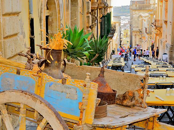 Sicilian cart in Noto, Sicily, on a celebration day Colorful street in Noto with typical Sicilian cart and outdoor restaurant tables on a celebration day. Noto, Sicily, Southern Italy - August 2014 noto sicily stock pictures, royalty-free photos & images