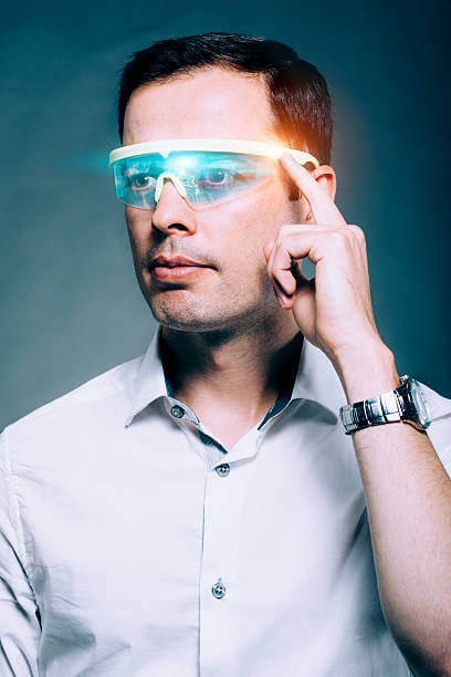 Man wears technology glasses with a visual screen Man is using a pair of glasses with built-in screen. He is adjusting the content by touching the glasses on the side. Concept of wearable technology. head mounted display stock pictures, royalty-free photos & images