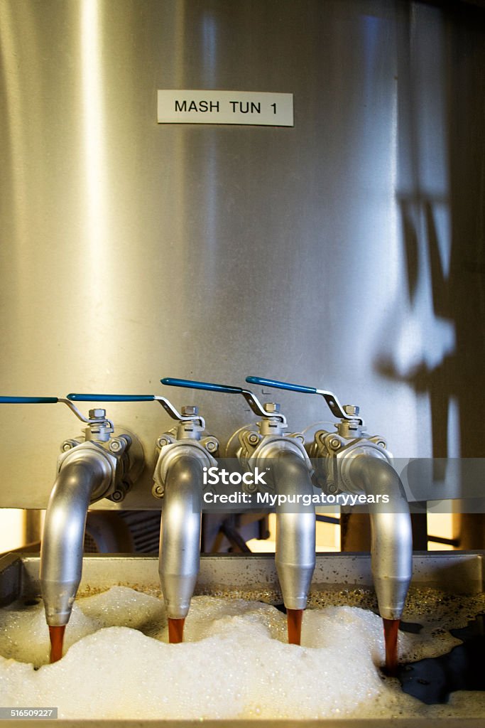 Beer flowing out of Mash-tun The start of real ale production as brown liquid flowsw out of the mash tun at a brewery. Adult Stock Photo