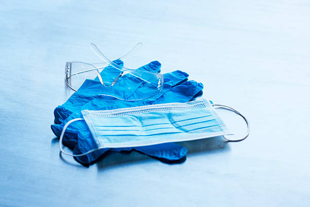 Contaigen Mask Gloves and Glasses A contaigen mask, a pair of nitrile gloves, and a pair of safety glasses. All things need to protect yourself from communicable diseases. swine flu masks stock pictures, royalty-free photos & images