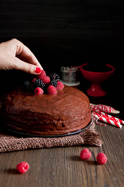 istock Woman's hand putting a blackberry on a chocolate cake 516510075