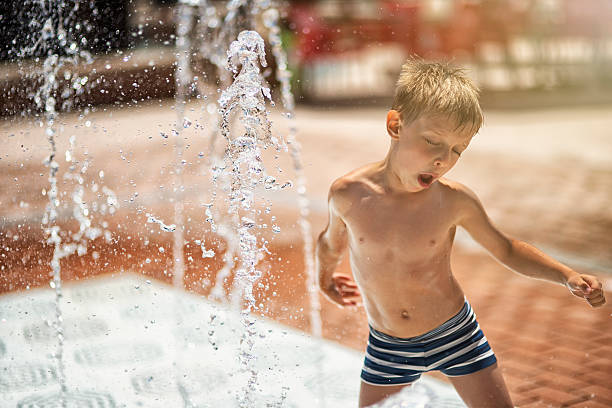 istock Little boy having fun in water park fountain 516511317