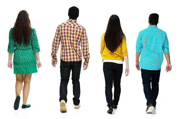 Rear view of four people walking together stock photo