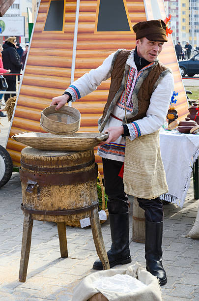Gomel, Belarus - March 12, 2016: Man is showing the work of old hand-mill during a Shrovetide entertainment outdoor 