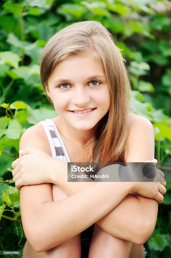 Summer, Spring, Preadolescent girl, blonde hair, smiling having fun sitting [b]Summer[/b], [b]Spring[/b], [b]Preadolescent[/b] girl, blonde hair, smiling having fun sitting on the grass, bushes behind her. 10-11 Years Stock Photo