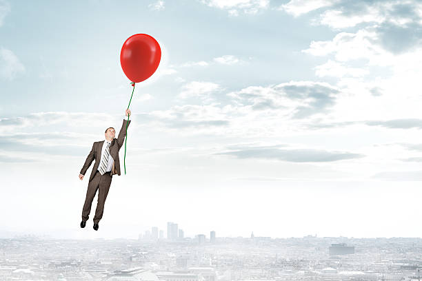 istock Businessman holding balloon and flying 516543600