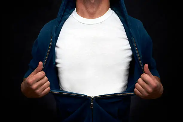 Hero pulling open blue blouse showing white t-shirt on blackboard background