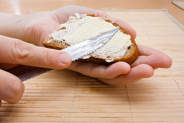 istock hands spreading butter on piece of rye bread 516548000