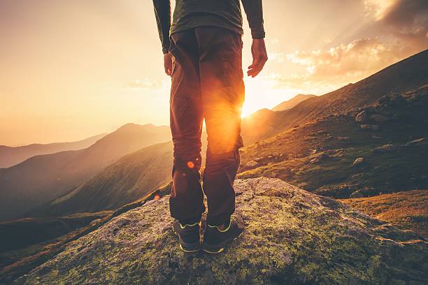 junger mann allein reisende füße stehen mit sonnenuntergang berge - happy land stock-fotos und bilder