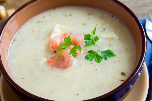 Vegetable cream soup with shrimps in bowl close up