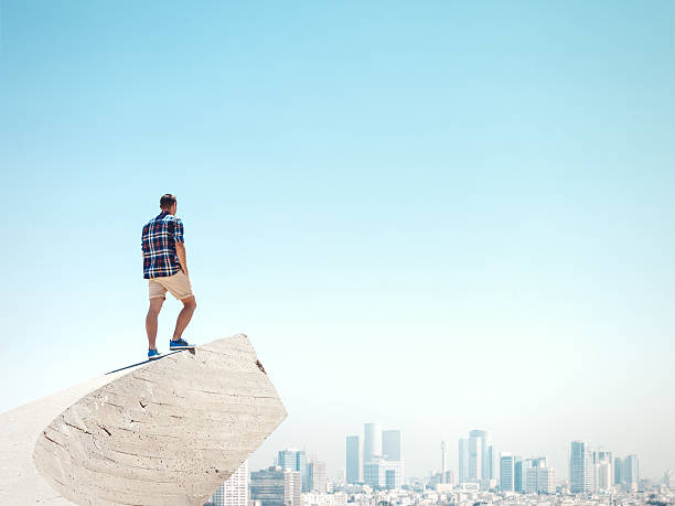 Young man standing on a cliff stock photo