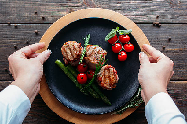 istock Food  serving. Waiter serving a pork dish. 516552410