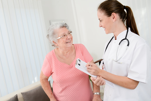 young doctor checking rehab medical progress to an elderly woman at home