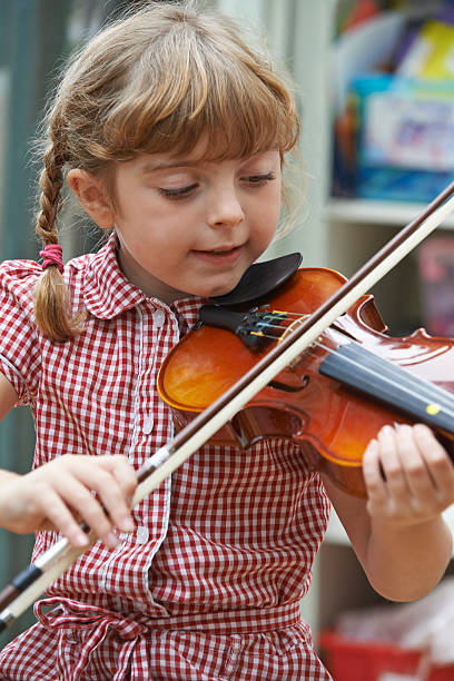 istock Young Girl At School Learning To Play Violin 516586325