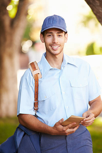 Mailman Walking Along Street Delivering Letters Smiling To Camera