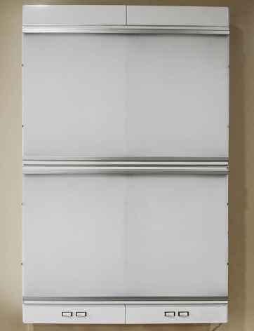 An unlit X-ray lightbox with no film on it hanging on the wall.