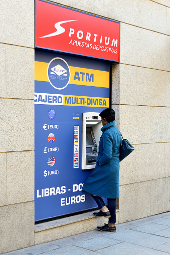 Madrid, Spain - February 19, 2016: Woman withdrawing money from the ATM in Madrid, Spain