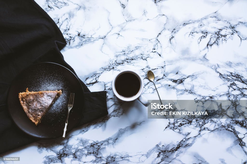 Homemade cake with cup of coffee Homemade cake with cup of coffee on black tea towel over marble kitchen countertop. Top view shot. Marble - Rock Stock Photo