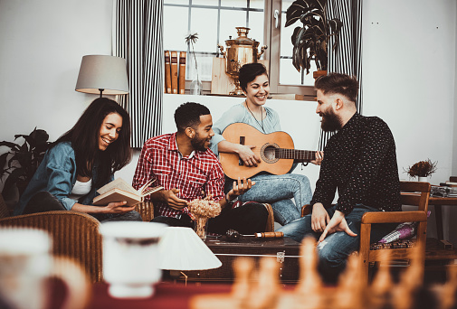 Happy group of friends singing and playing guitar