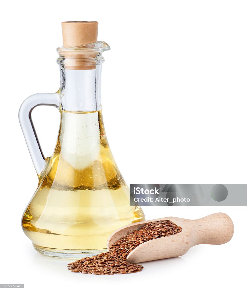 Linseed oil in glass bottle and flax seeds Linseed oil in glass bottle and flax seeds in wooden scoop isolated on white background Cooking Oil Stock Photo