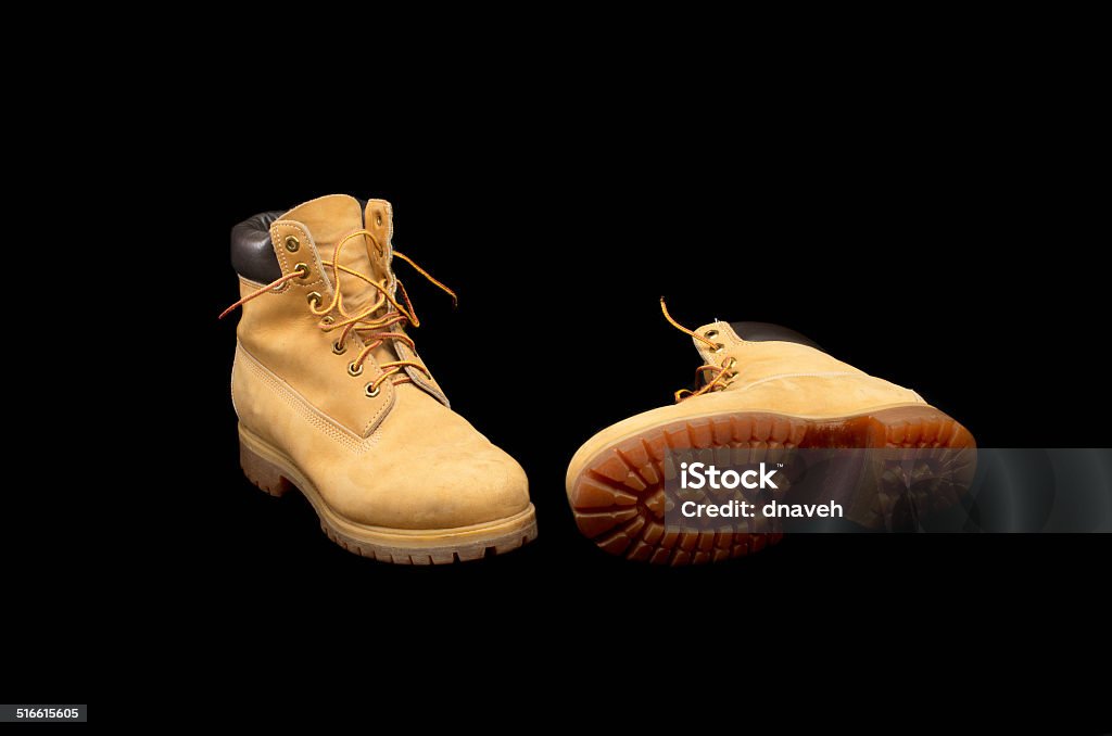 Authentic pair of 8 inch Yellow Work Boots Authentic pair of 8 inch Yellow Work Boots isolated on black showing the sole Adult Stock Photo