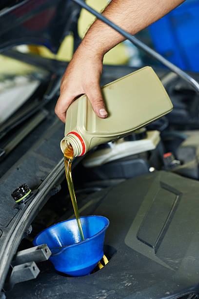 istock car mechanic pouring oil into motor engine 516617579