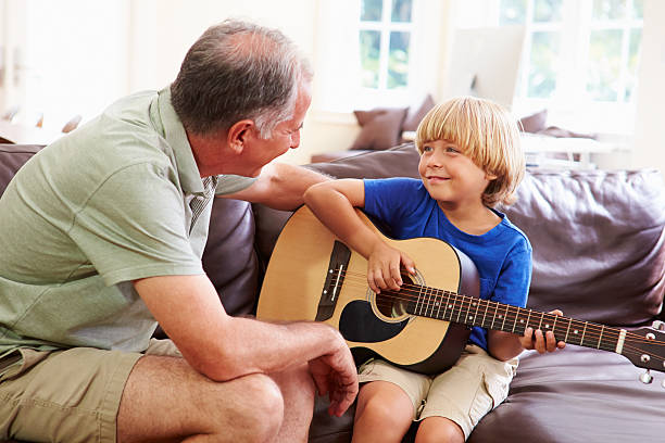 istock Grandfather Teaching Grandson To Play Guitar 516619477